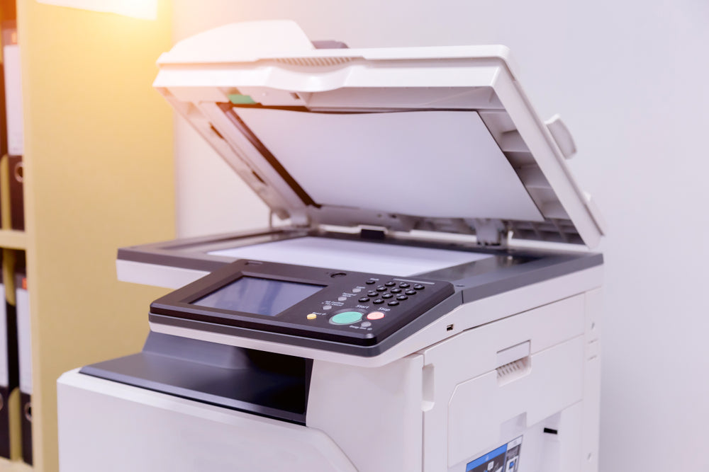 Office copy machine with the scanner lid open, sunlight streaming in.